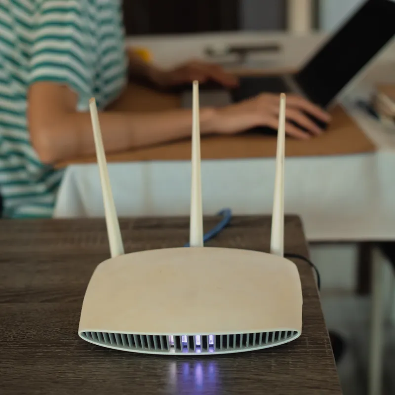 Routeur wifi à trois antennes posé sur une table en bois à la maison