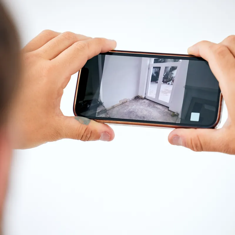 Mains photographiant une pièce vide avec un smartphone pour la scanner