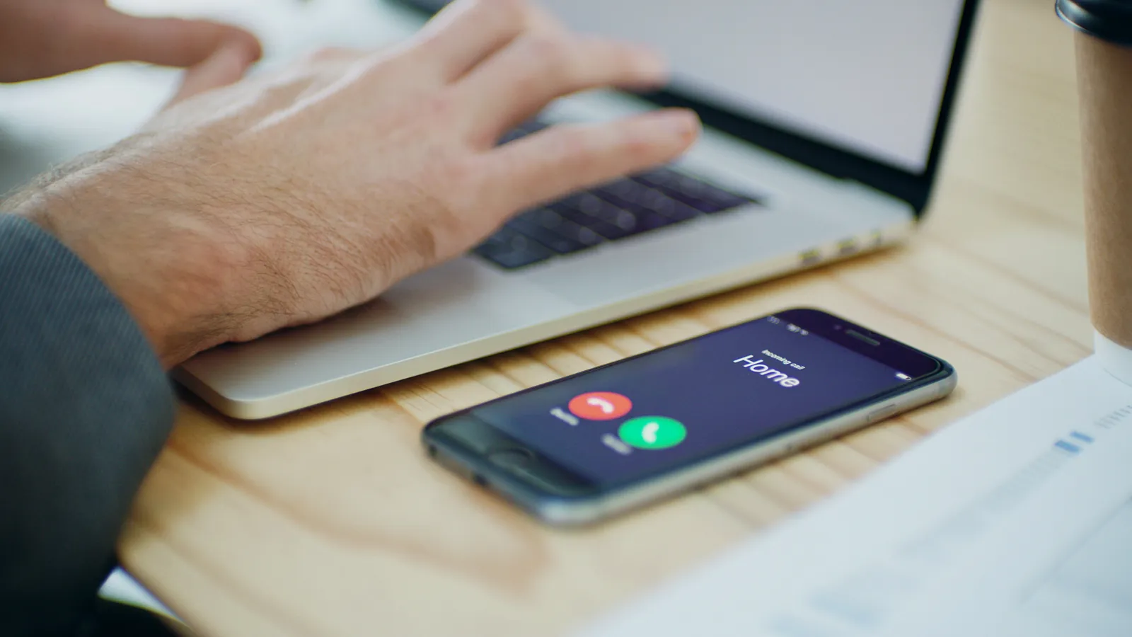 Smartphone recevant un appel entrant sur un bureau à côté d'un ordinateur portable